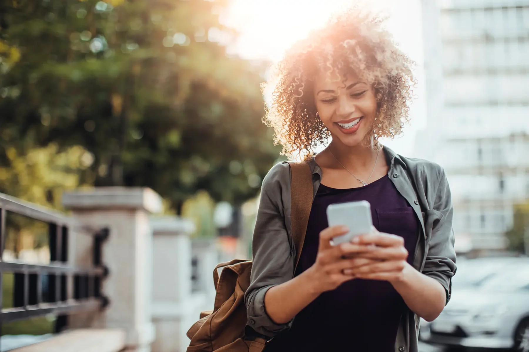 Young woman walking down the street smiling at her phone