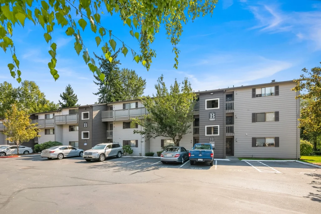 building exterior with large trees and parking