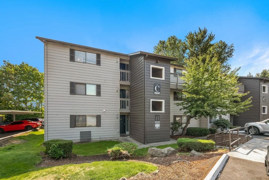 Building exterior with large trees and covered parking