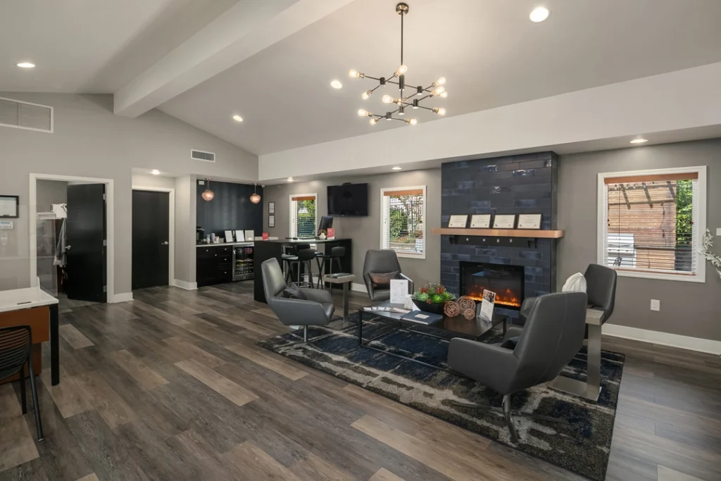 Clubhouse lounge with chairs around a fireplace and kitchenette